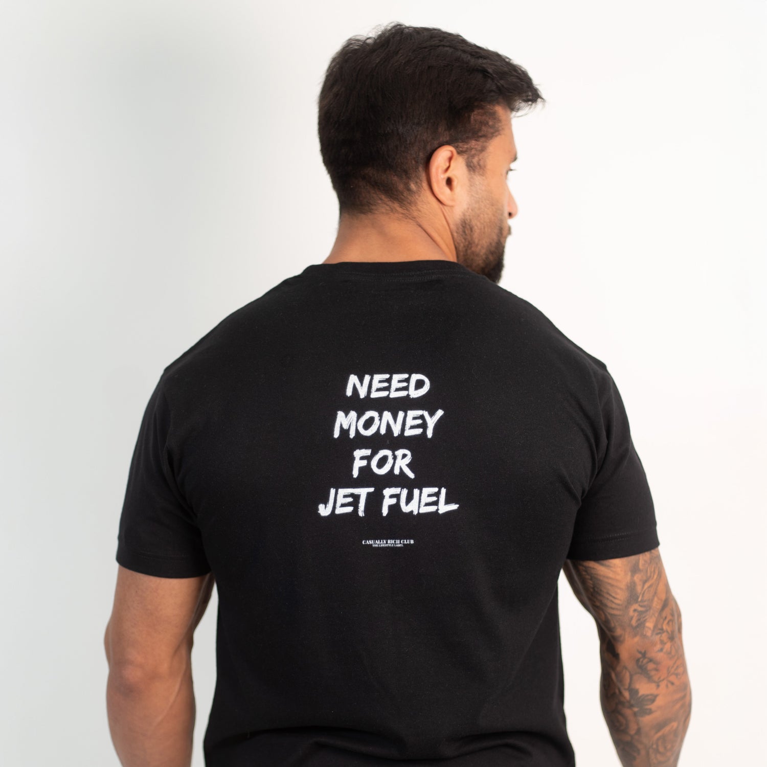 Man wearing a black t-shirt with text on the back, standing against a white background